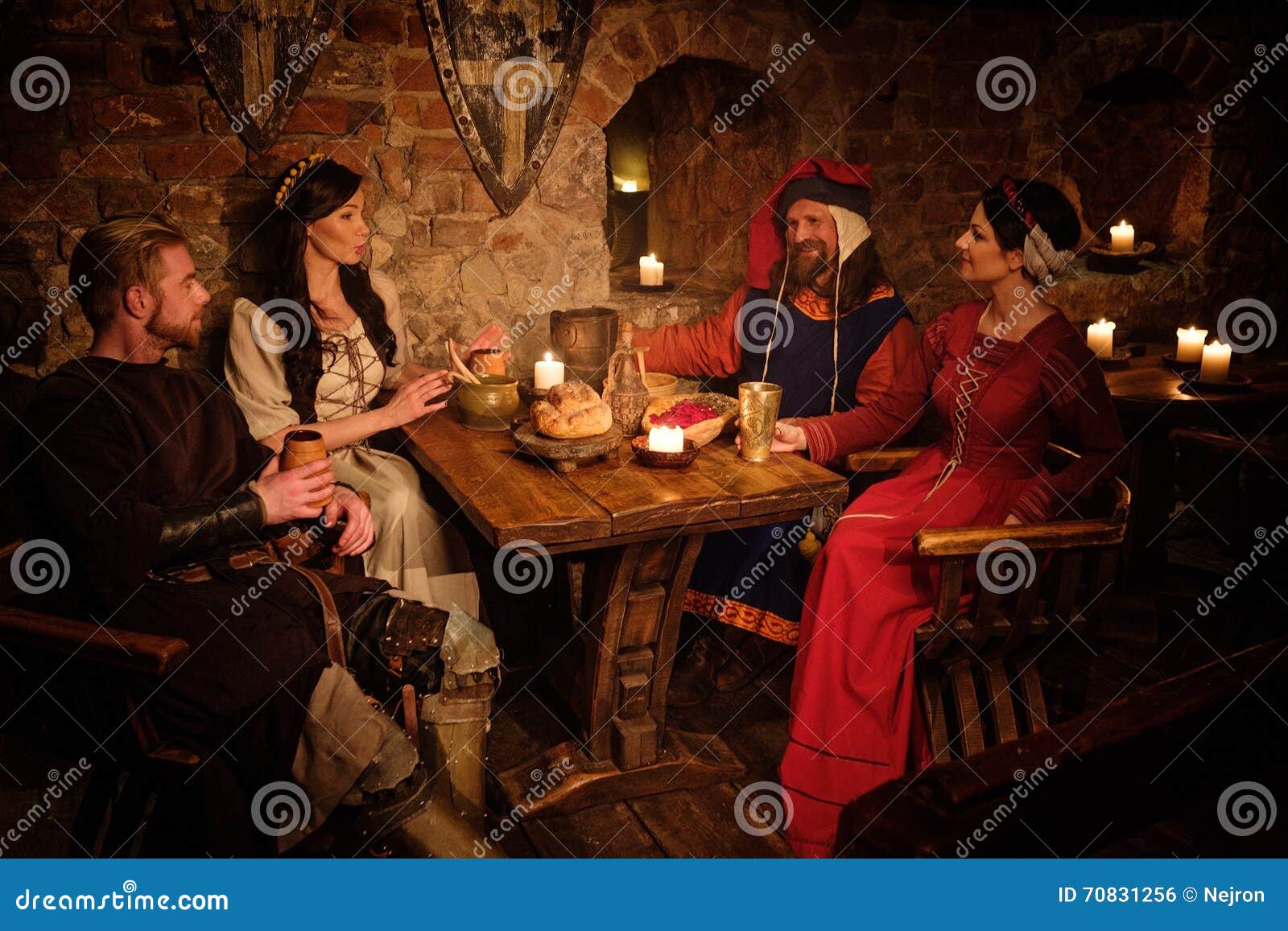 Medieval People Eat and Drink in Ancient Castle Tavern. Stock Photo
