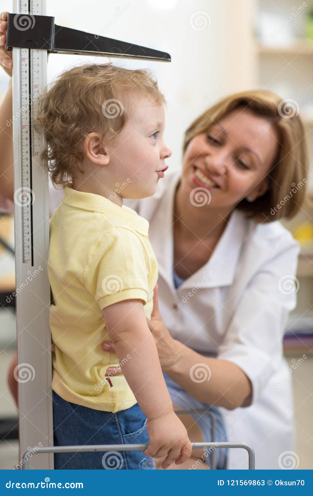 Medique medidas do menino de sorriso da criança do crescimento do pediatra no escritório médico, perfil