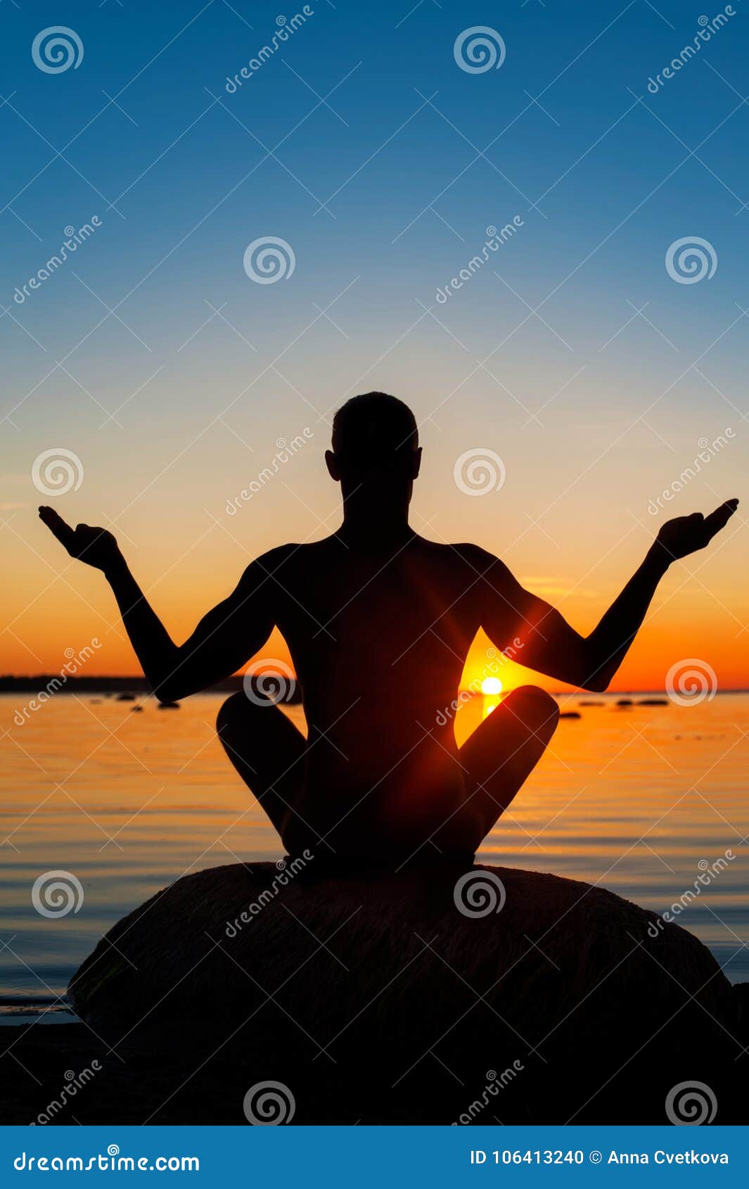 Meditating man silhouette on vibrant sunset background. Multicolored summertime vertical outdoors image. View from backside.