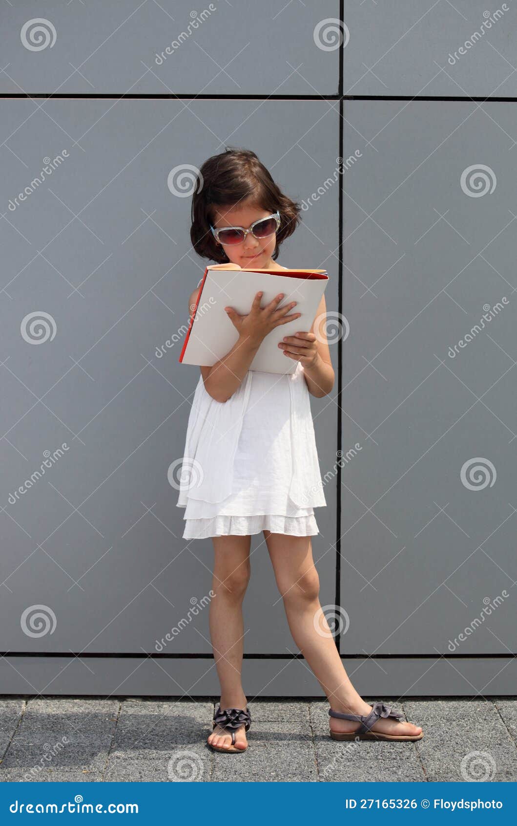 Meisje dat met zonnebril een tijdschrift leest. Toekomstige onderneemster die zich voor een de bureaubouw muur bevindt en een bedrijfstijdschrift leest.