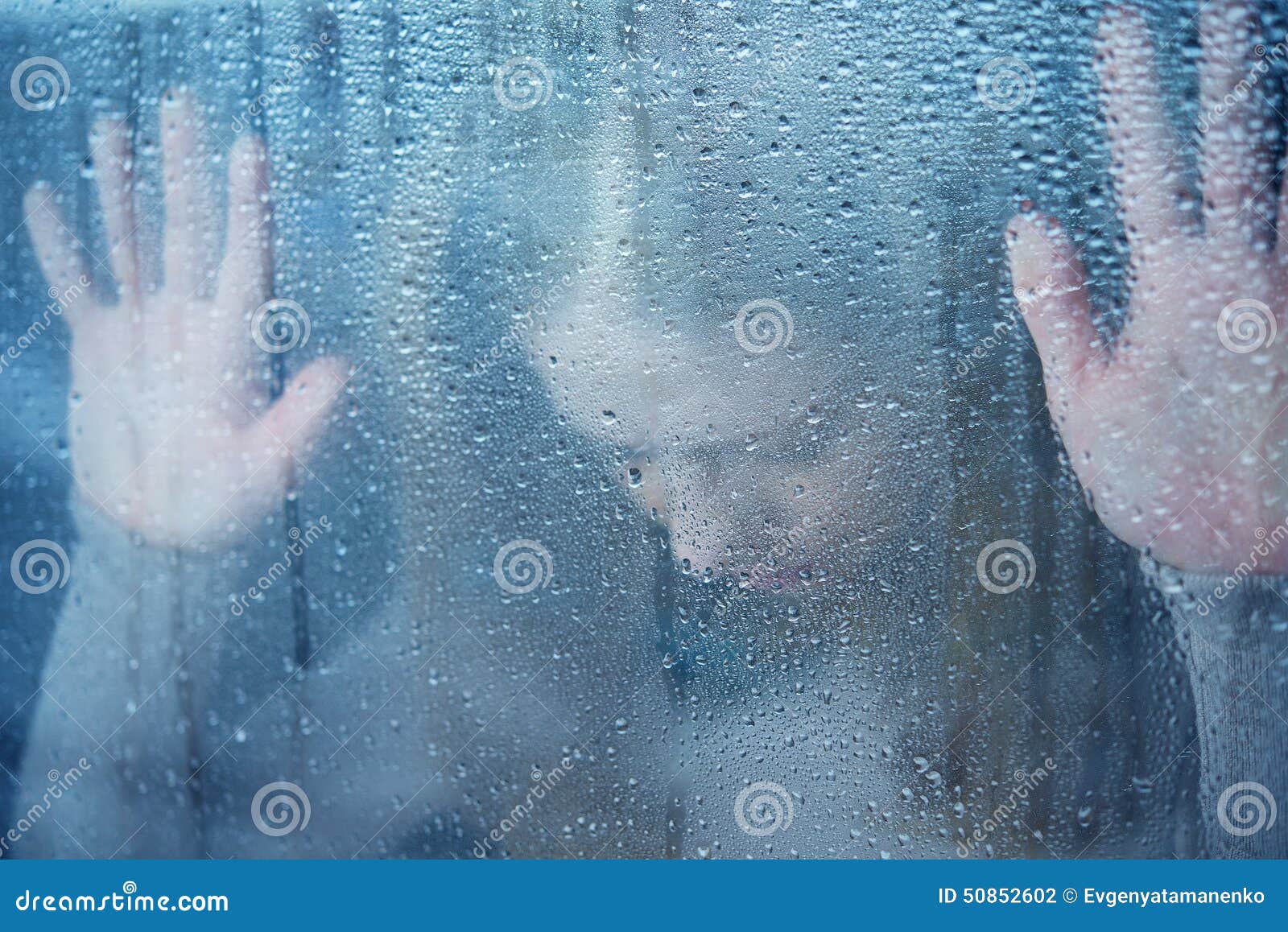 melancholy and sad young woman at the window in the rain