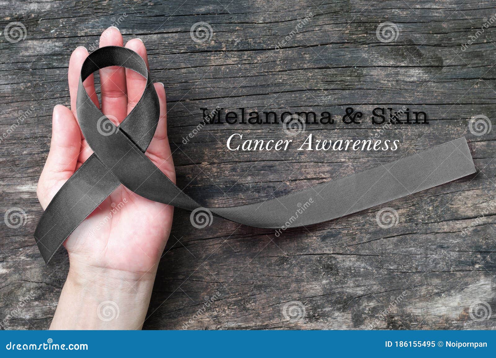 melanoma and skin cancer black awareness ribbon on human helping hand old aged background
