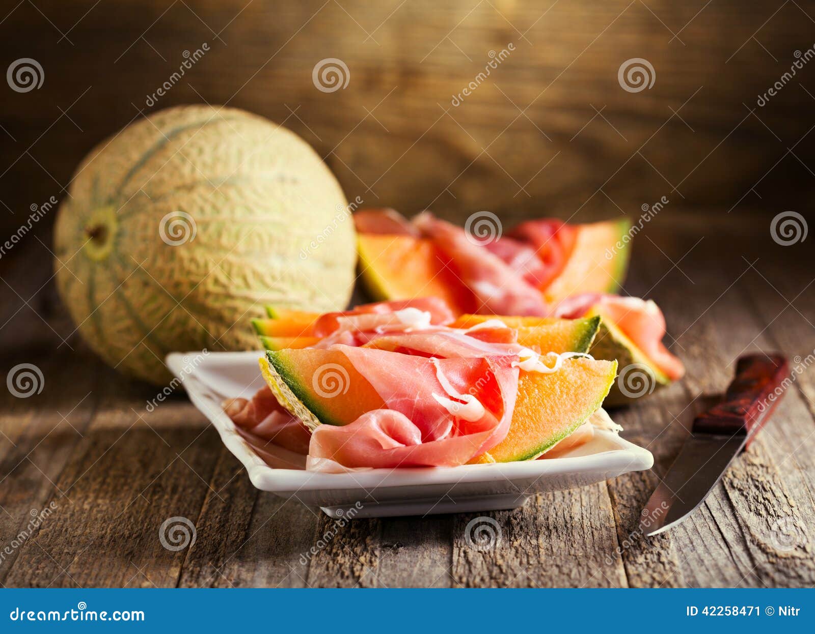 Melão do cantalupo com prosciutto. Melão do cantalupo com o prosciutto no fundo de madeira