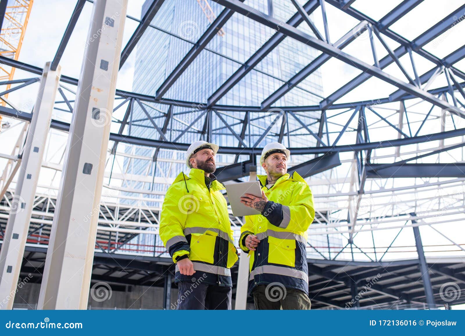 Men Engineers Standing Outdoors on Construction Site, Using Tablet