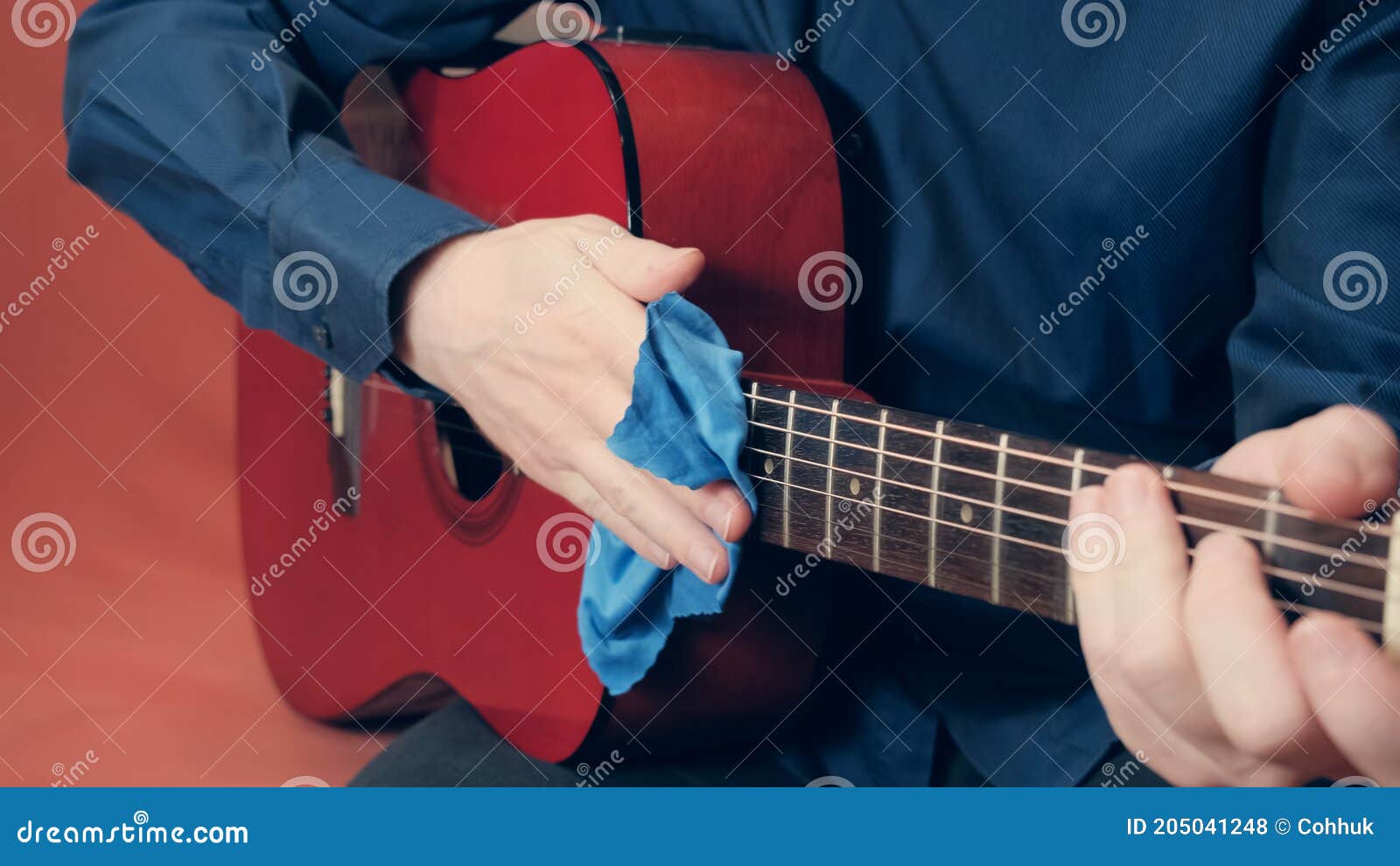 men hands take care of acoustic guitar wiping tool from dust