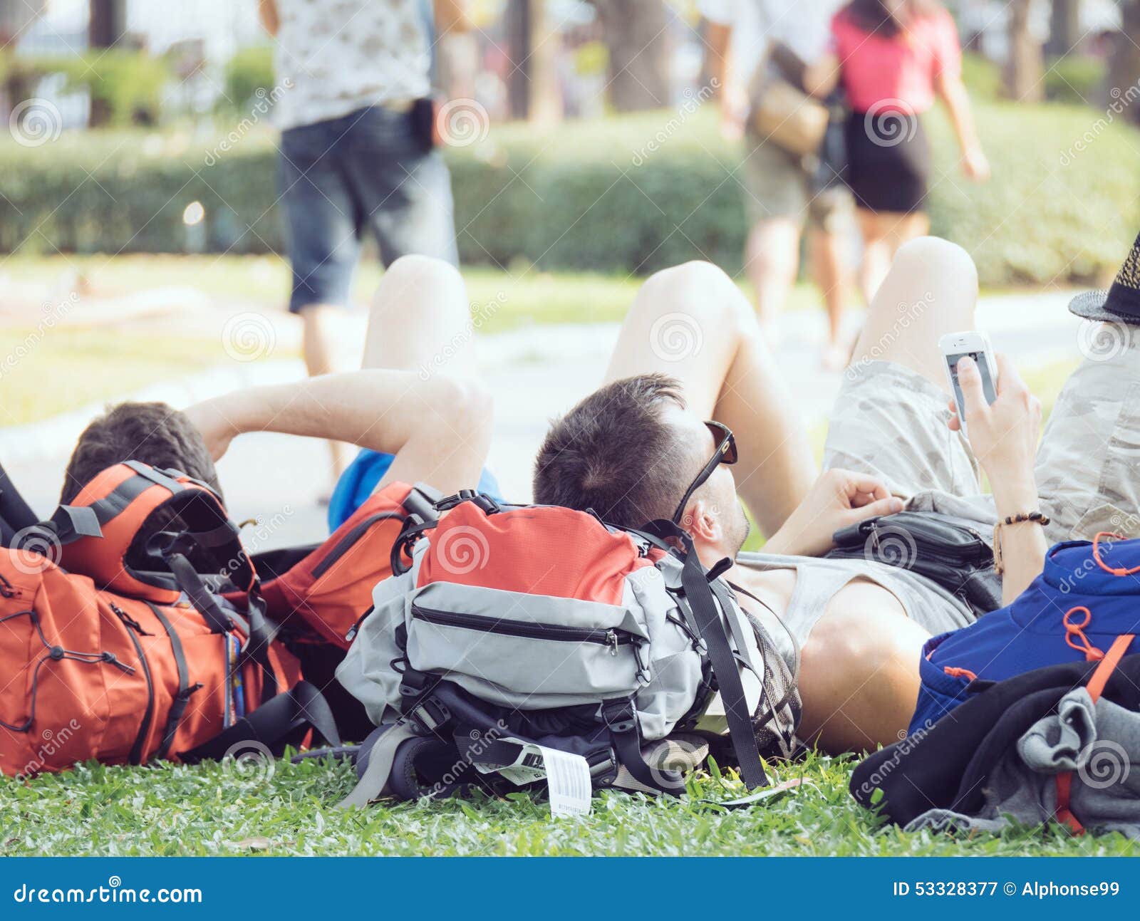 Three men laying down on the grass play mobile phone