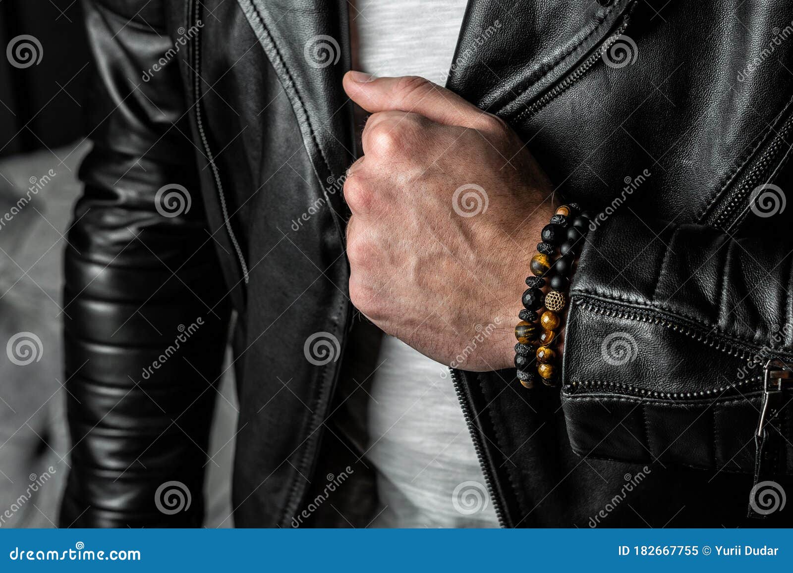 men`s bracelet made of precious stones and minerals, on a hand in a leather jacket. close-up