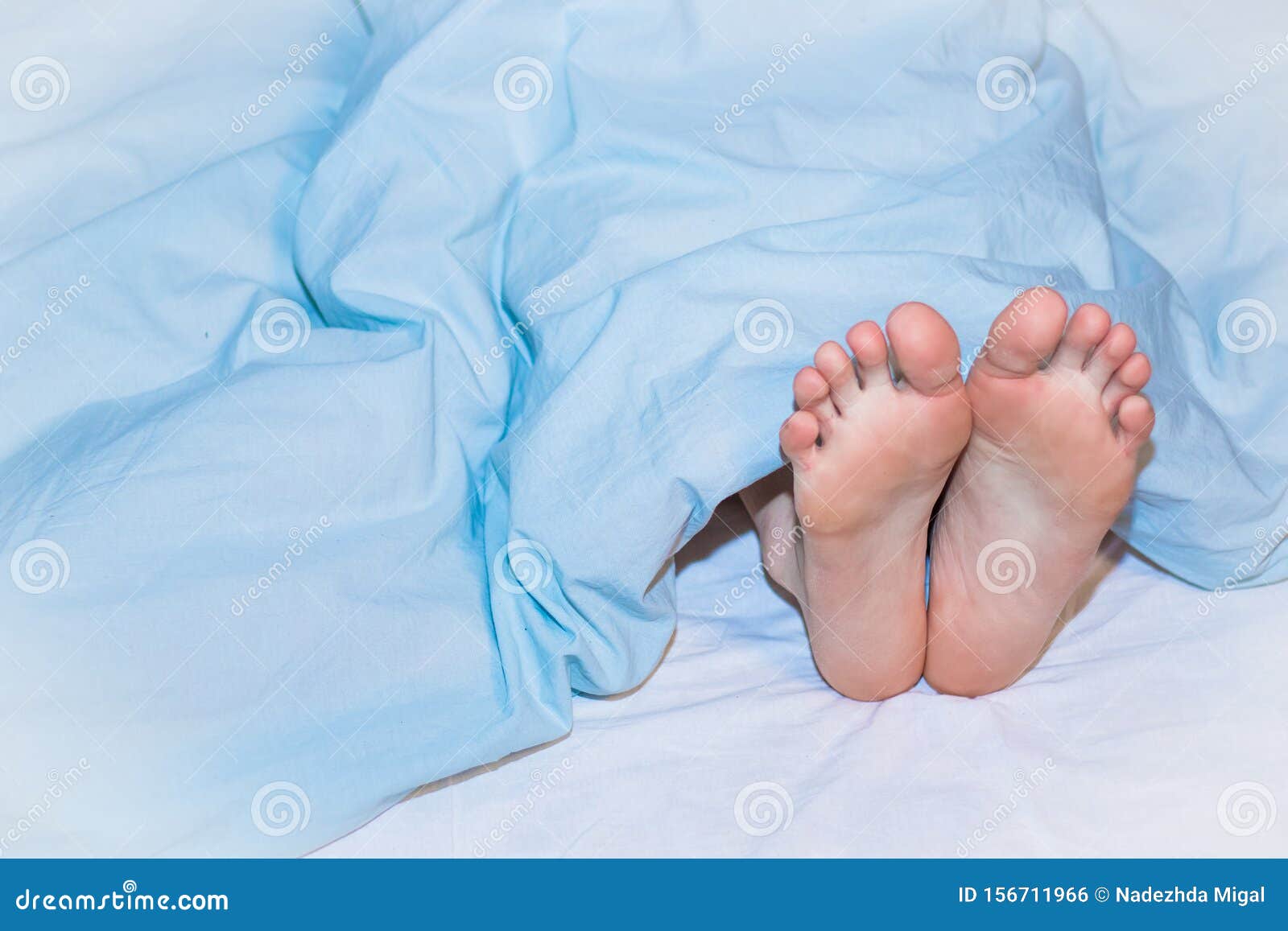 Men`s Feet Sticking Out from Under the Blue Blanket. Stock Photo Image of background, healthy