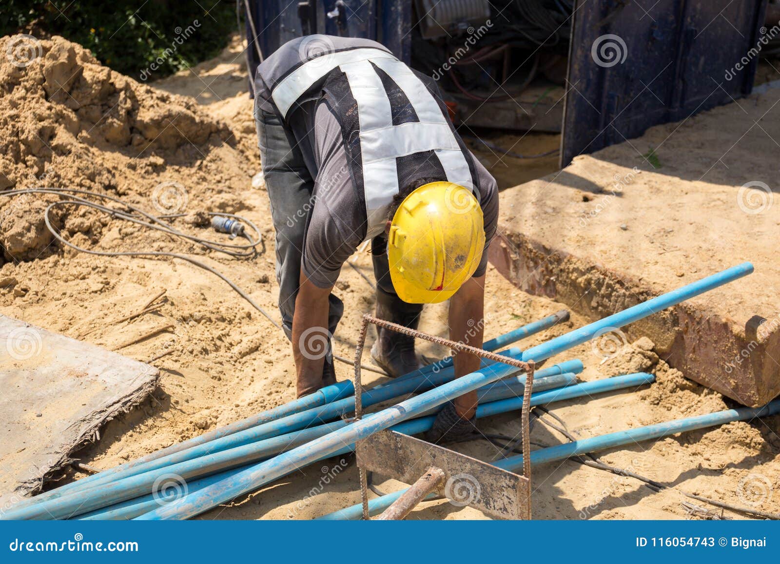 Worker Picking Up Blue Water Pipe on Construction Site Stock Image