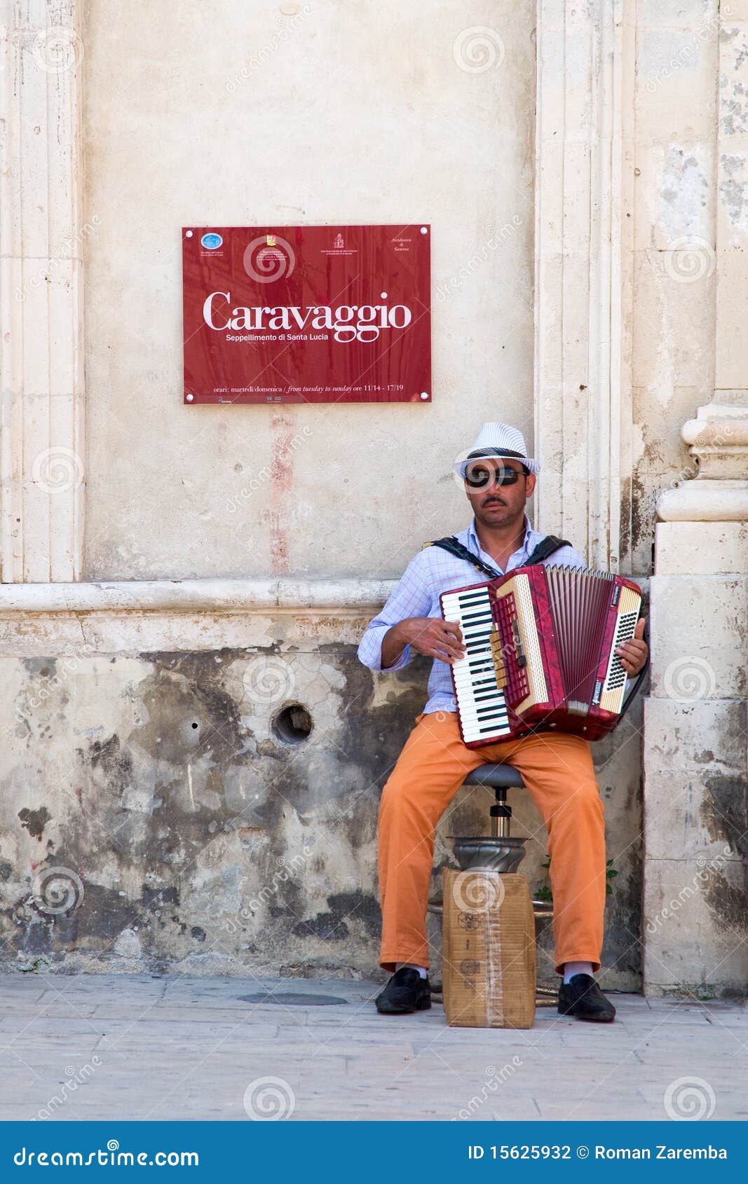 Mendiant - accordéoniste. Un mendiant jouant l'accordéon et priant devant une église.
