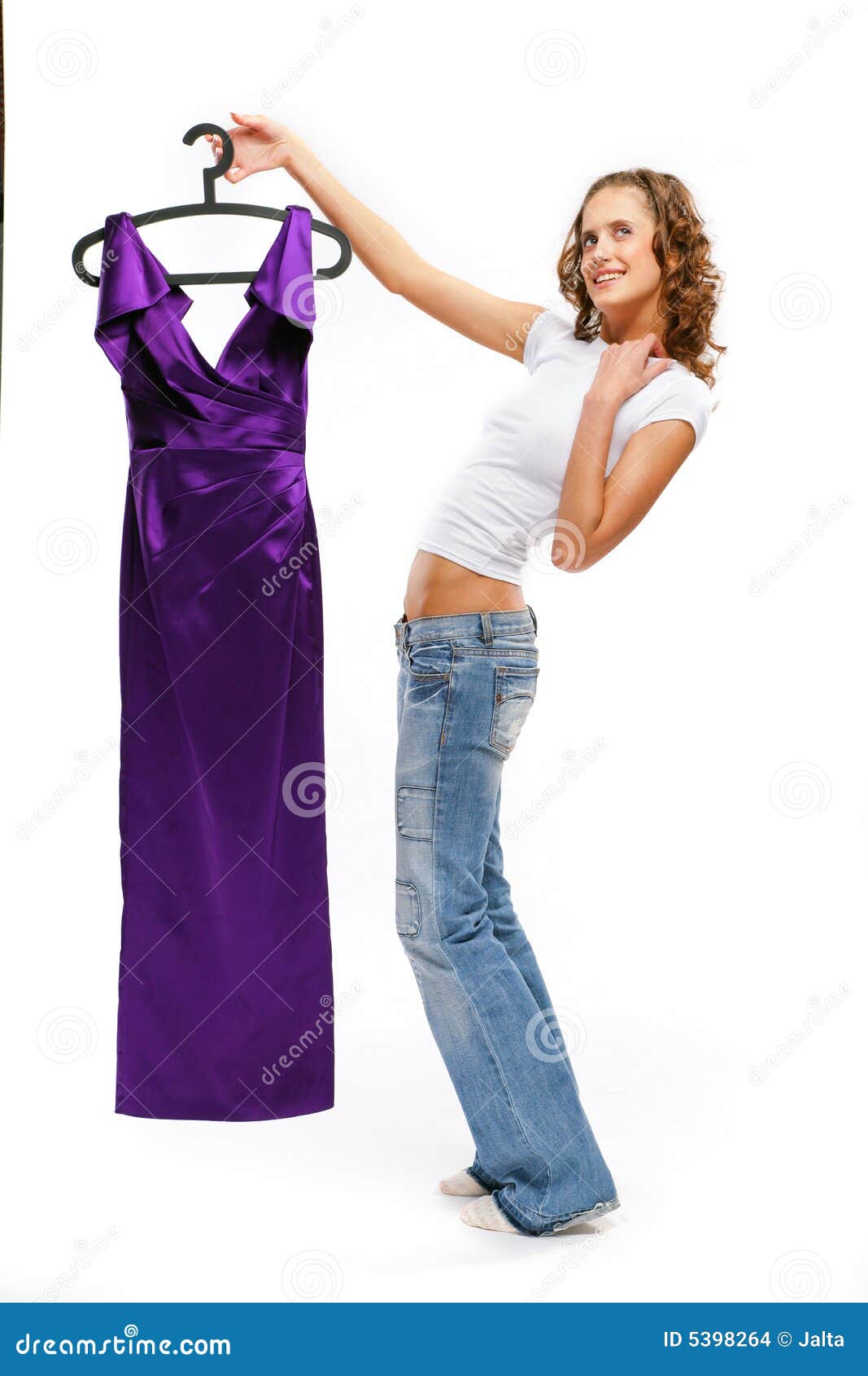 A menina bonita nas calças de brim prende um vestido do lila