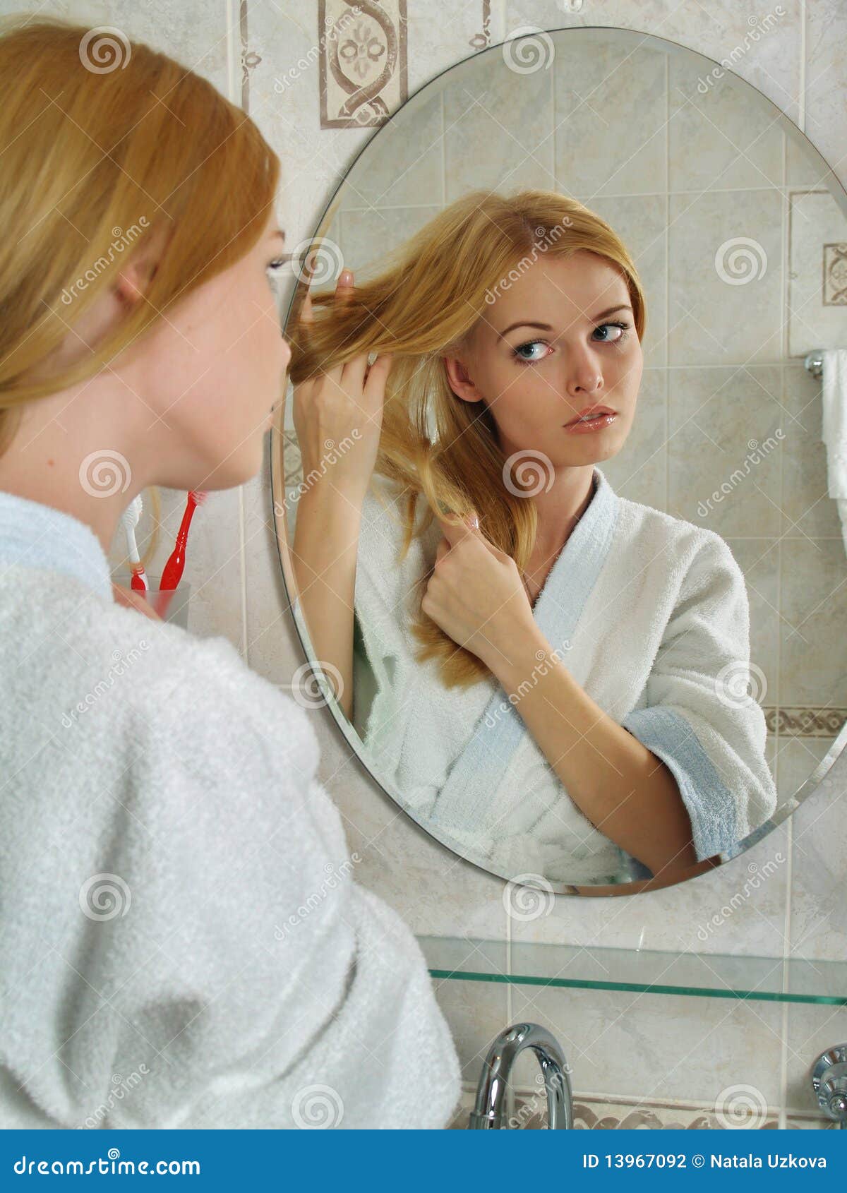 A Menina Bonita Olha Em Um Espelho Em Um Banheiro Foto de Stock - Imagem de  cara, adulto: 13967092