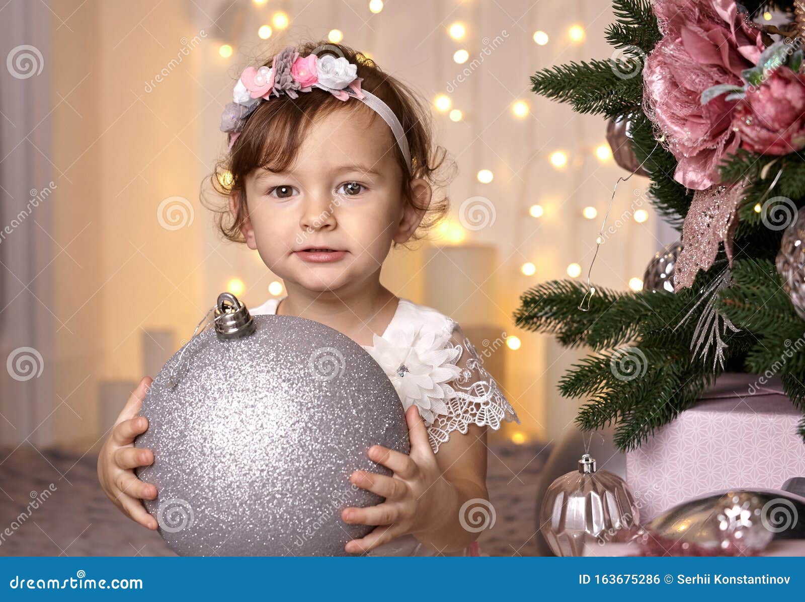 Menina Bonitinha Brincando Com Uma Bola Grande De Prata Para Decorar Uma  árvore De Natal Foto de Stock - Imagem de bebê, clau: 163675286