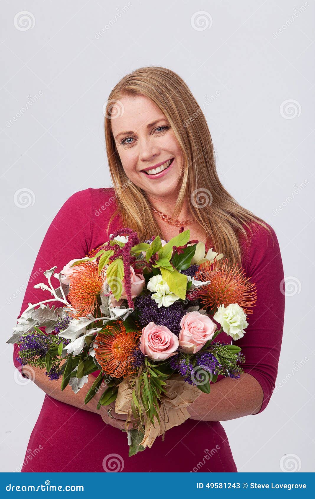 Menina com flores. Fêmea loura que guarda um grande grupo de flores na frente de sua cara