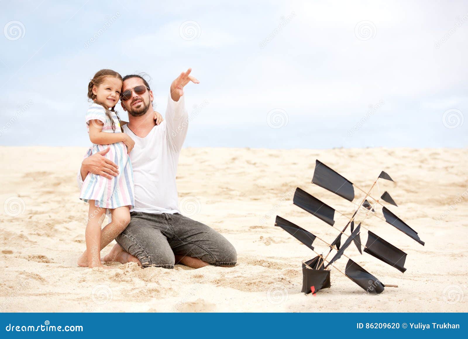 Menina com seu oceano feliz da costa do papagaio do voo do pai. Encalhe a menina bonito com seu oceano exterior da costa do papagaio feliz do voo do pai