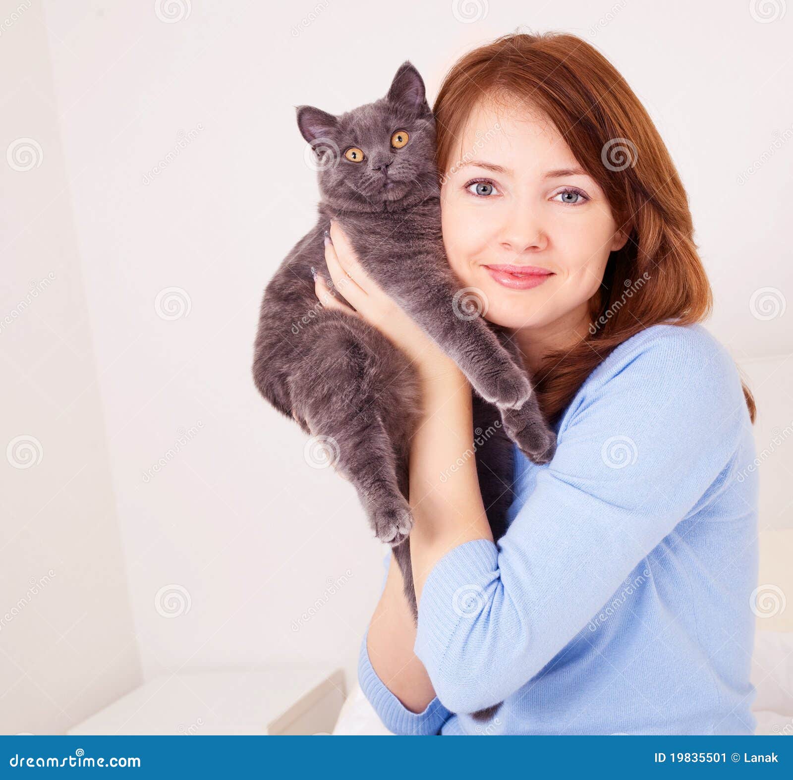 Menina com um gato. Mulher consideravelmente nova com seu gato na cama em casa