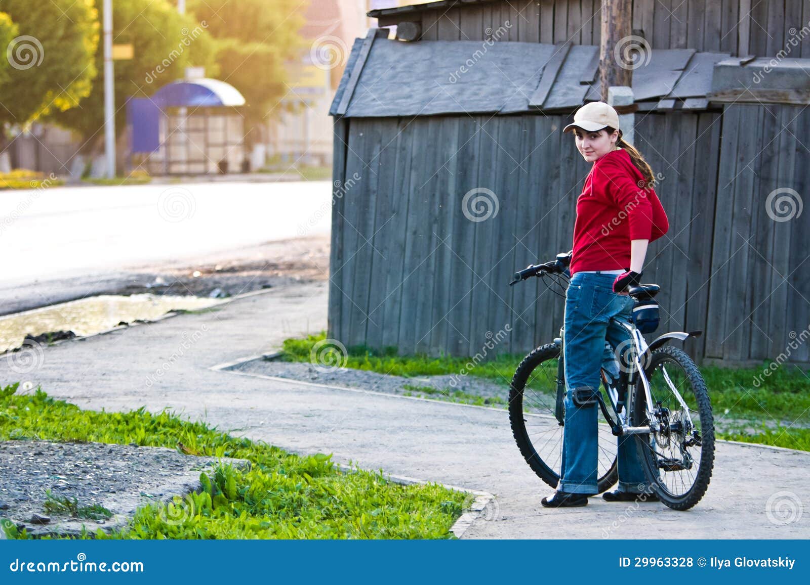 Menina com uma bicicleta no verão que olha para trás