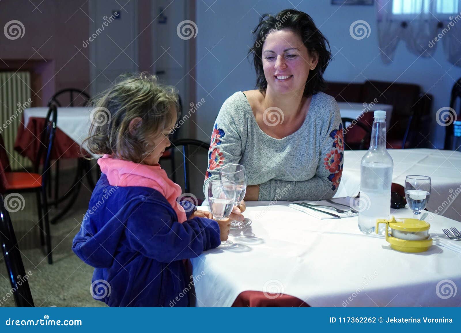 A menina faz um brinde com a mãe. A menina loura faz um brinde com a mãe