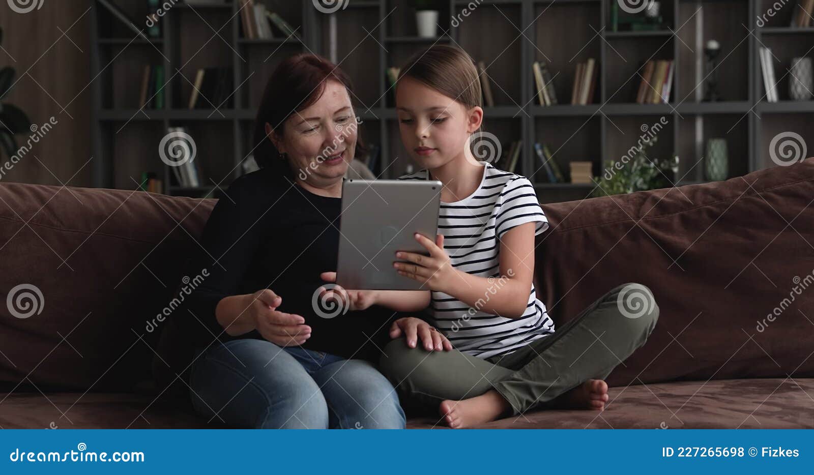 menina bonitinha sentada no chão usando tablet digital tocando a