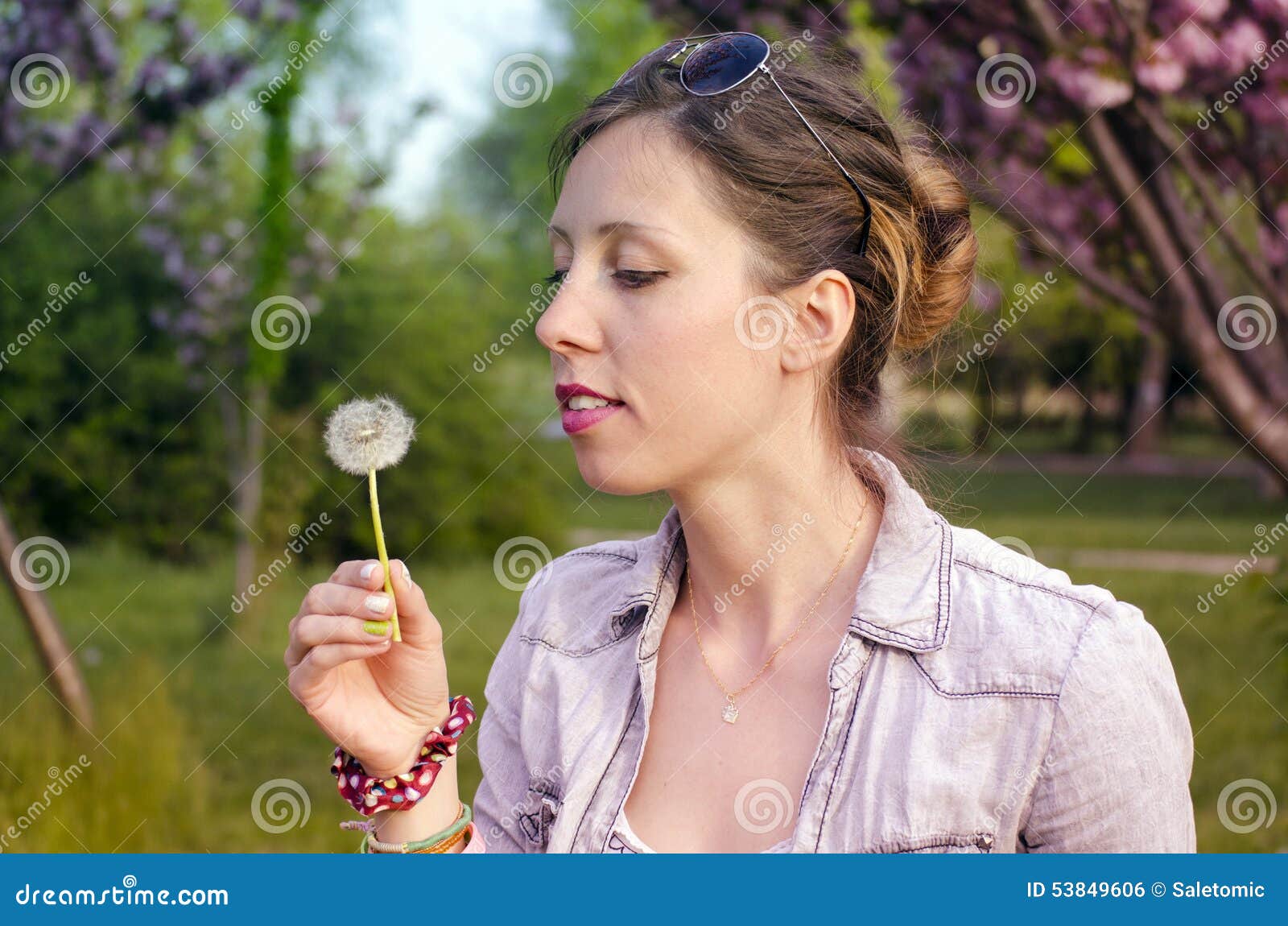 Menina moreno que guarda um dente-de-leão. Menina moreno que prepara-se para fundir um dente-de-leão em um parque