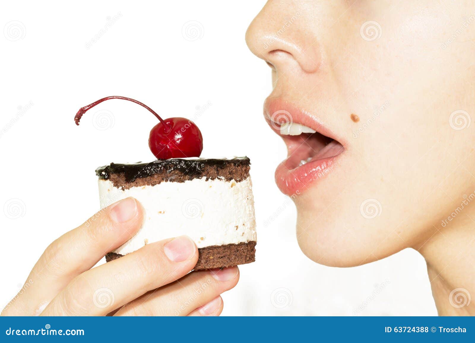 Menina que come o bolo de chocolate com a cereja na crosta de gelo superior na placa Fundo branco