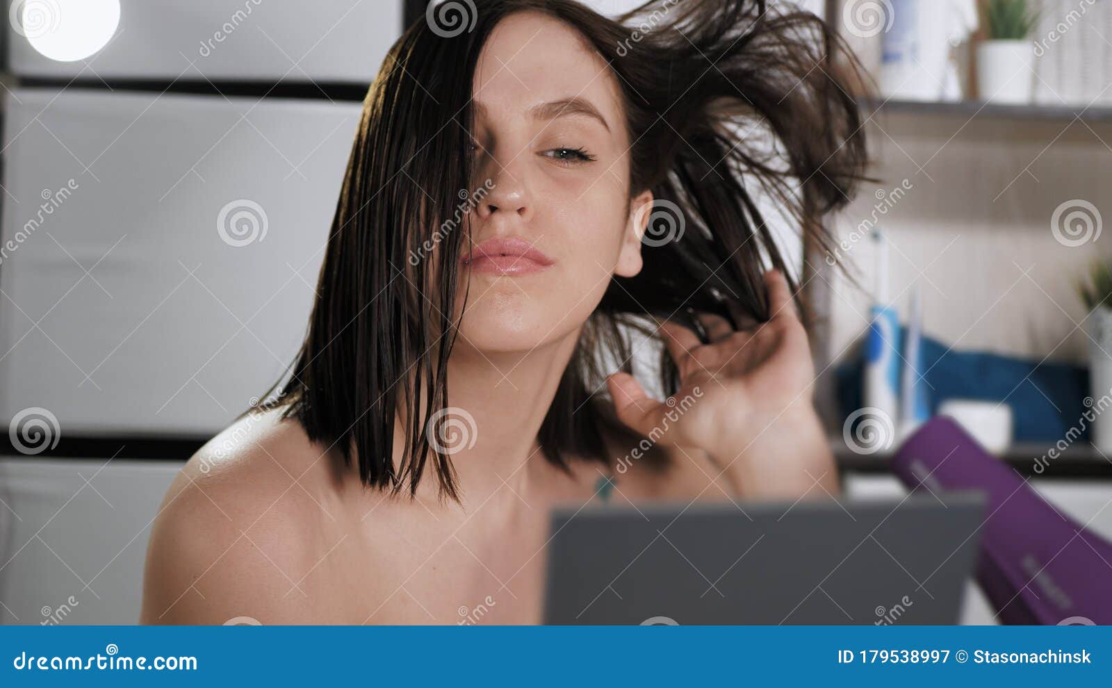 A mão de uma mulher segura um secador de cabelo preto sobre um