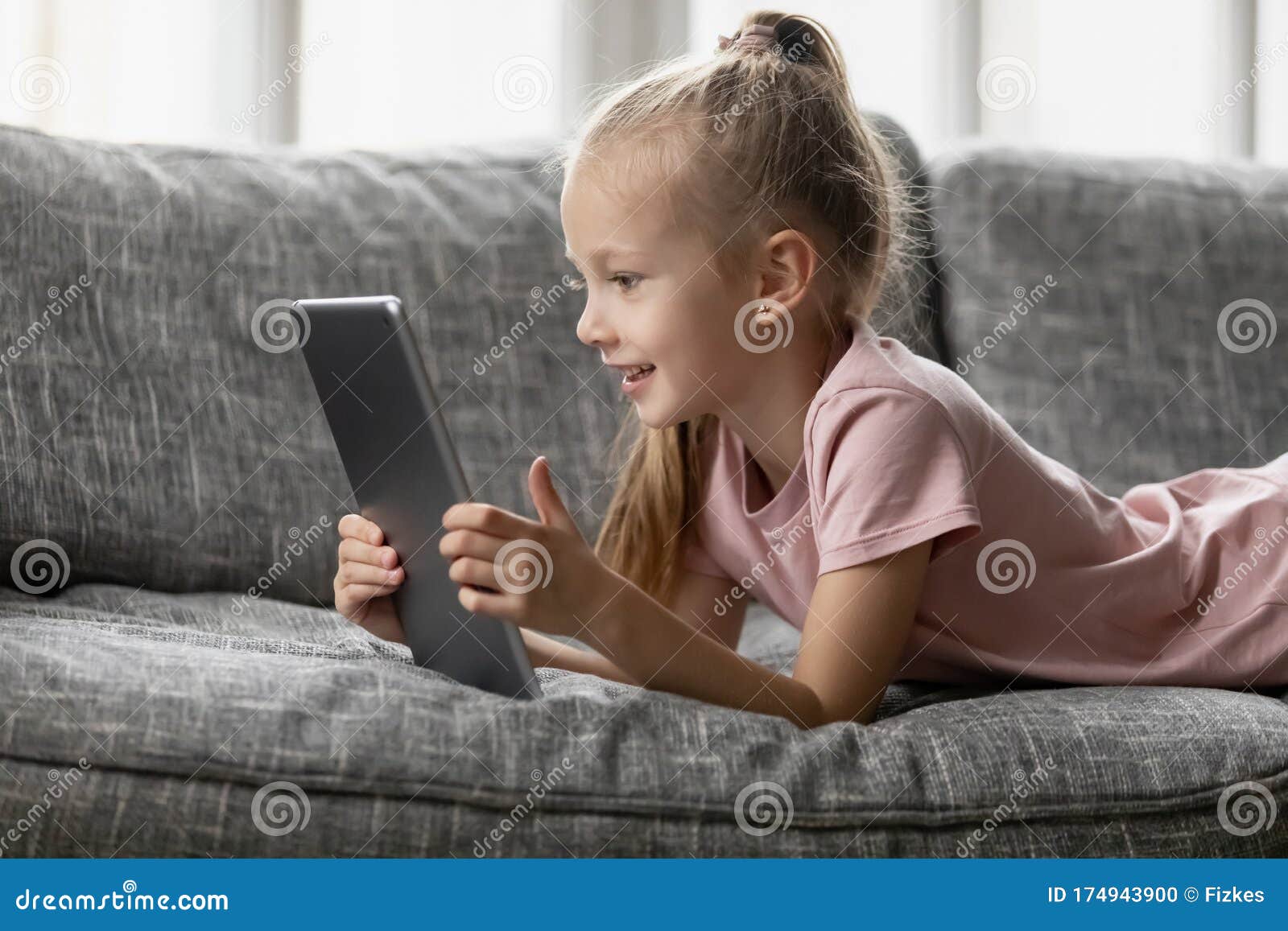 Sorridente menina deitada no sofá confortável, gostando de jogar jogo  online no computador tablet digital. viciado em tecnologia, criança feliz  usando aplicativos engraçados, informações de navegação na web.