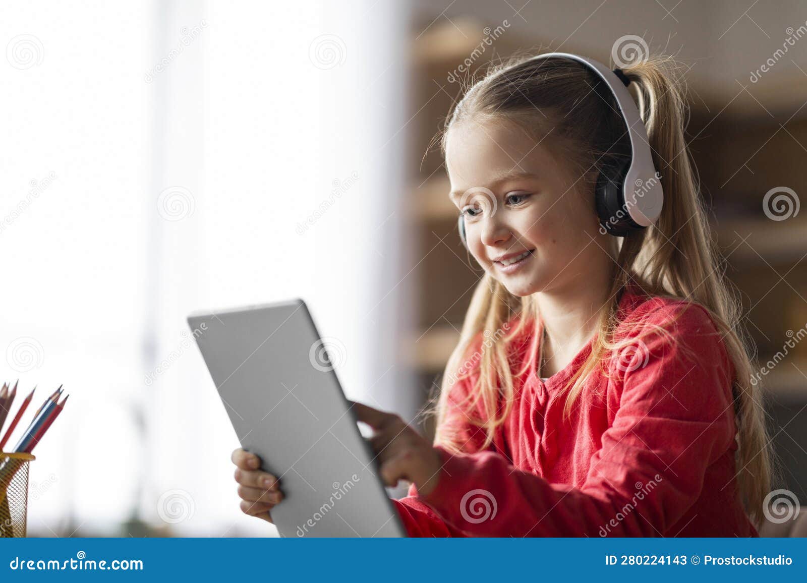menina bonitinha sentada no chão usando tablet digital tocando a