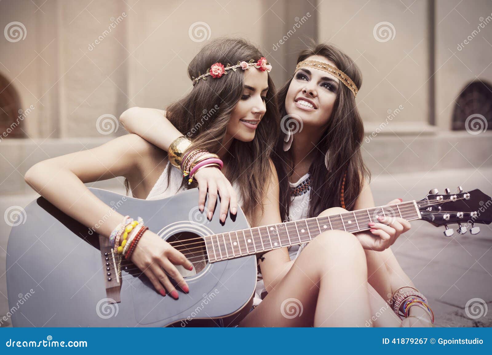 Meninas de Boho na rua. Amigos à moda bonitos que jogam a guitarra