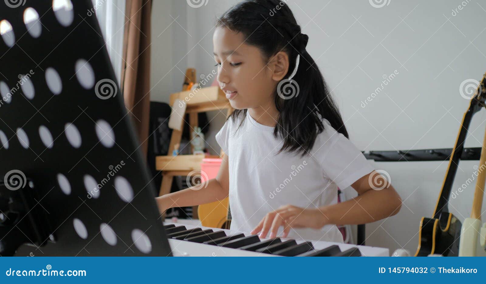 Criança asiática aprendendo a tocar piano online em casa