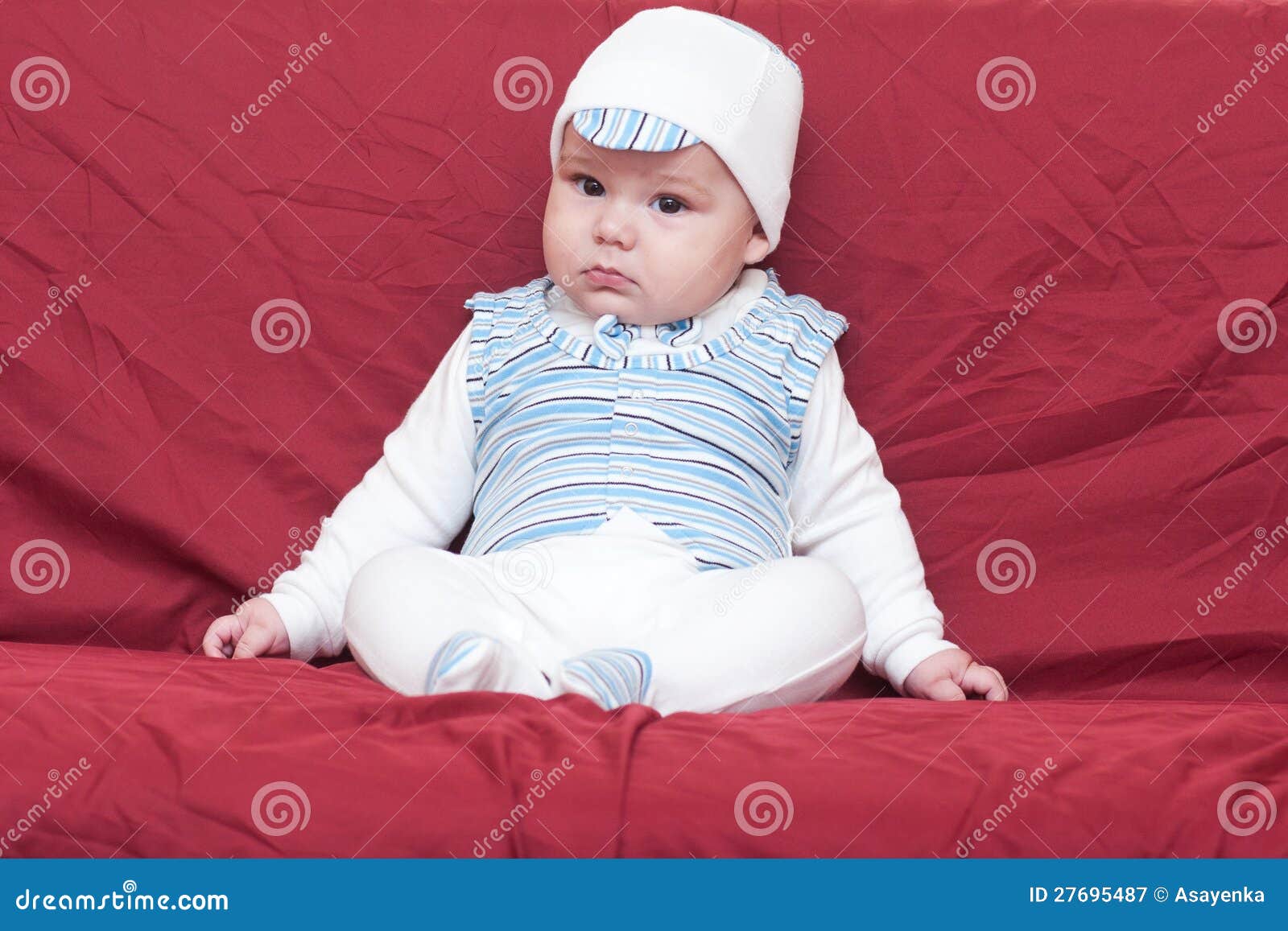 Menino bonito no tampão que senta-se no estúdio