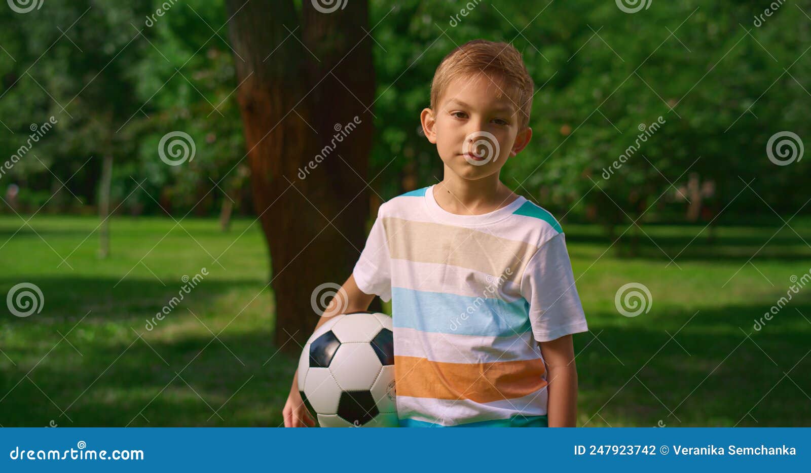 Um garoto segurando a velha bola de futebol antes de começar um jogo de  futebol