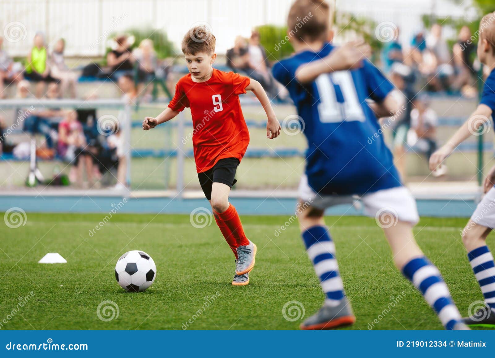 Jogo De Futebol. Crianças Jogando Futebol. Meninos Jovens Chutando Bola De  Futebol No Campo De Esportes. Crianças Jogando Jogo De Torneio De Futebol  No Campo. Juventude Jogo De Futebol Europeu Foto Royalty