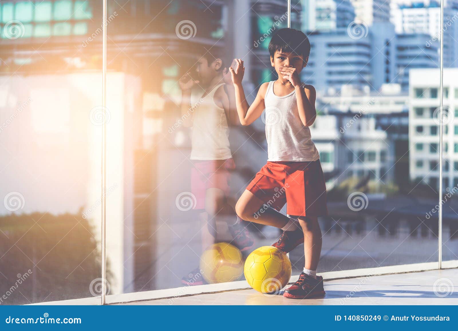 Menino Do Jogador De Futebol Que Pisa Na Bola Na Sala Imagem de