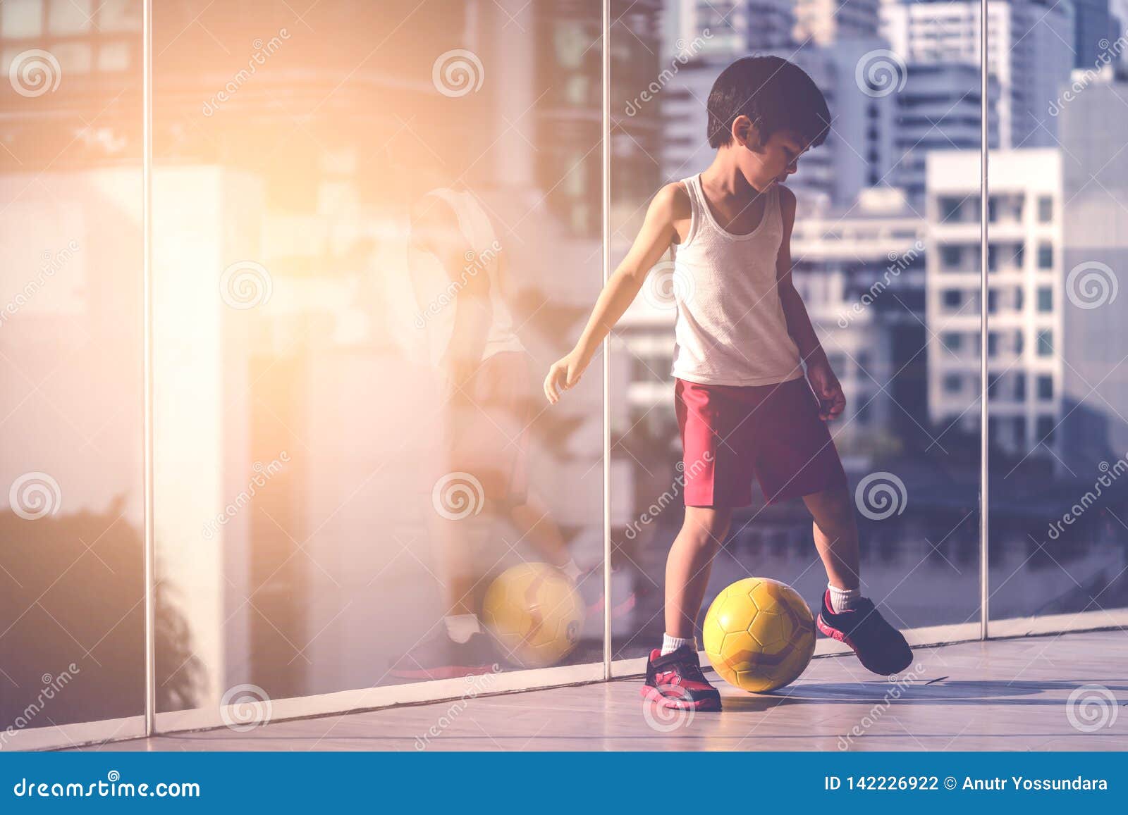 Menino jogador de futebol está pisando na bola na sala