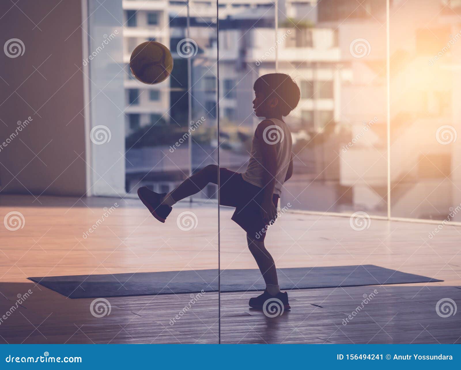 Menino Do Jogador De Futebol Que Pisa Na Bola Na Sala Imagem de