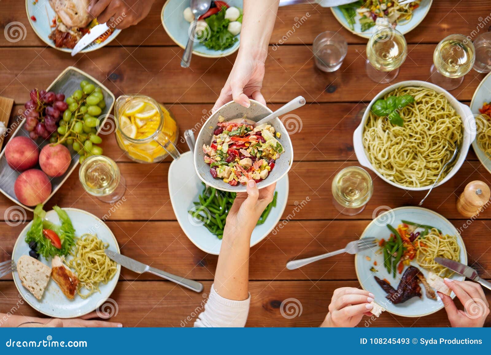 Mensen die salade eten bij lijst met voedsel. Voedsel, het eten en vrije tijdsconcept - mensen met salade die diner hebben