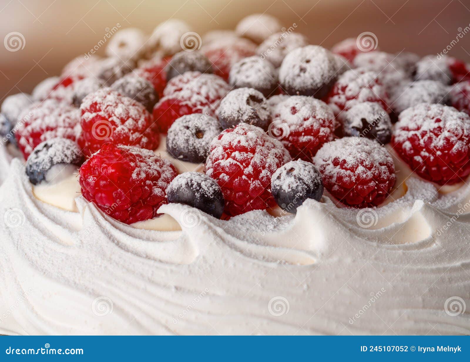 Meringue Cake with Blueberries and Raspberries on Plate on Green