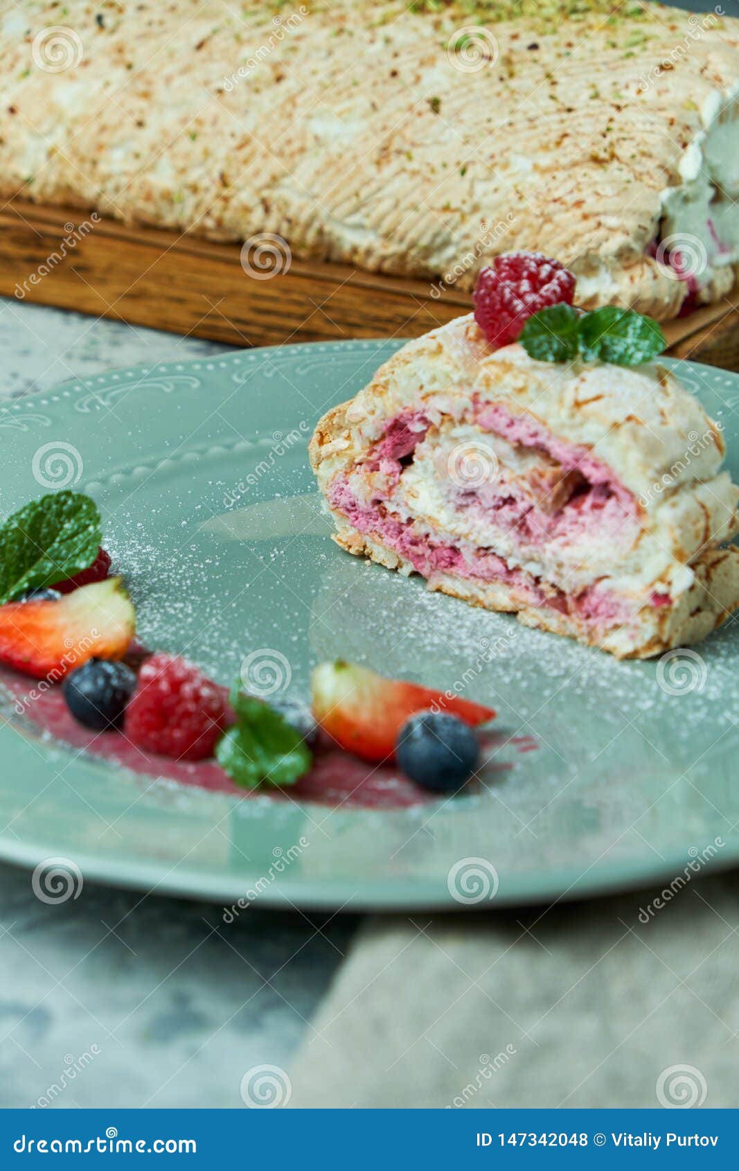 Meringue Cake Roll Slice on a Plate with Berries, on a Gray Background