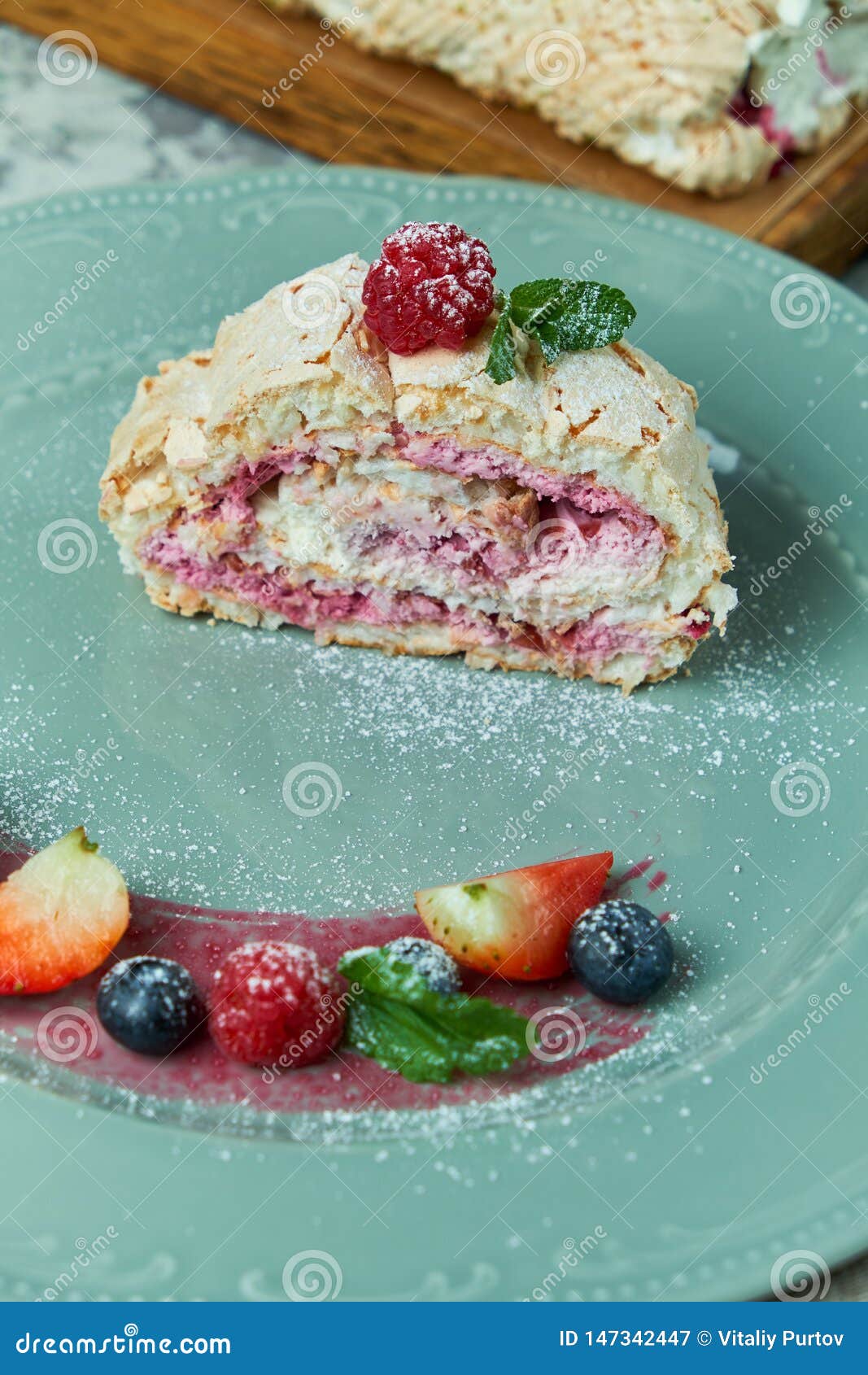 Meringue Cake Roll Slice on a Plate with Berries, on a Gray Background