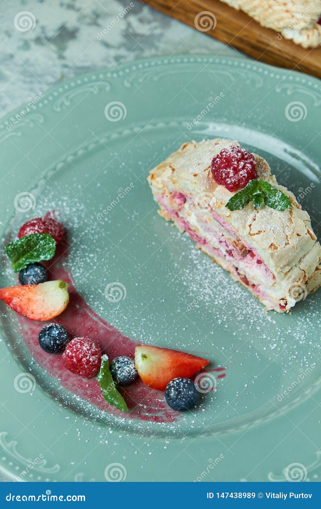 Meringue Cake Roll Slice on a Plate with Berries, on a Gray Background