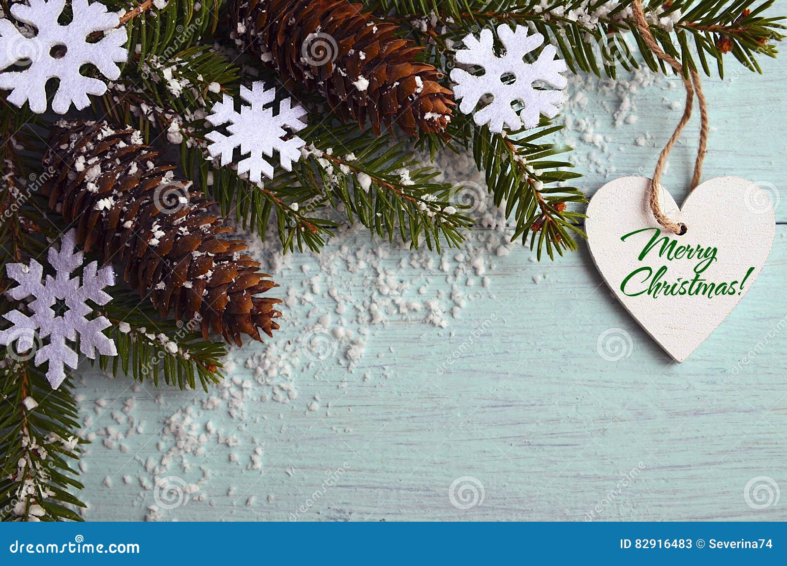 Merry Christmas greeting card.Decorative snowflakes,fir cones,heart and snowy fir tree branch on light blue background.Christmas decoration.Selective focus.