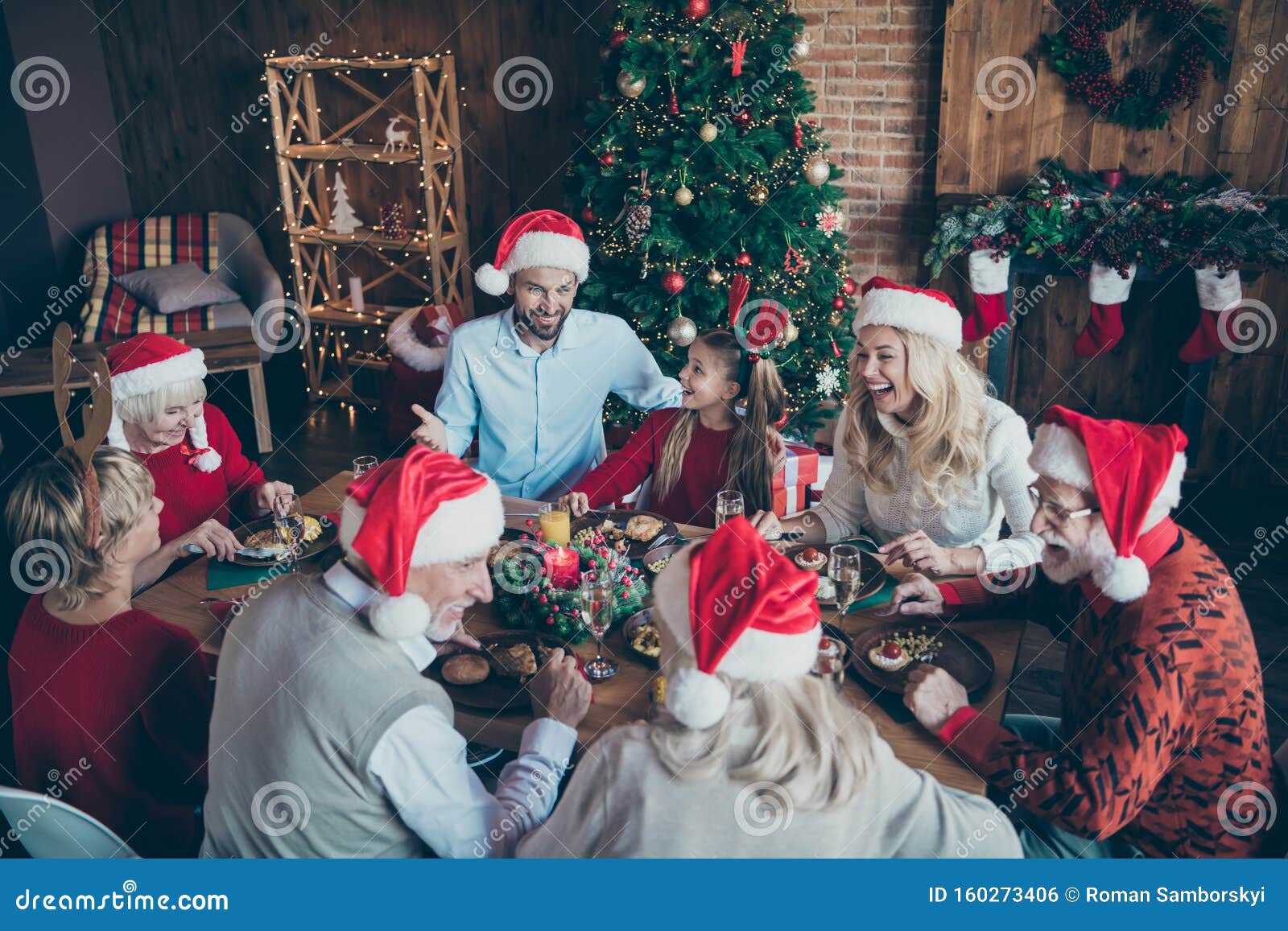 merry christmas large family reunion gathering meeting sit table have x-mas feast father in santa claus hat cap joke