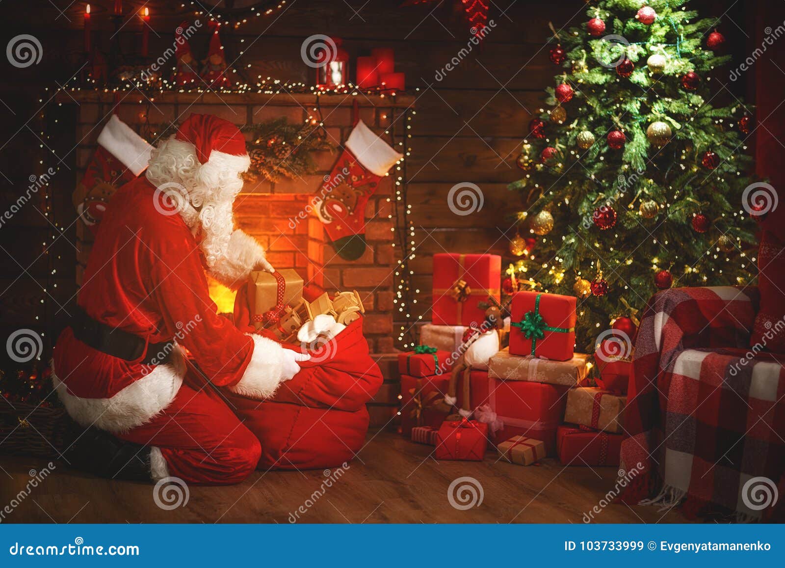 merry christmas! santa claus near the fireplace and tree with gi