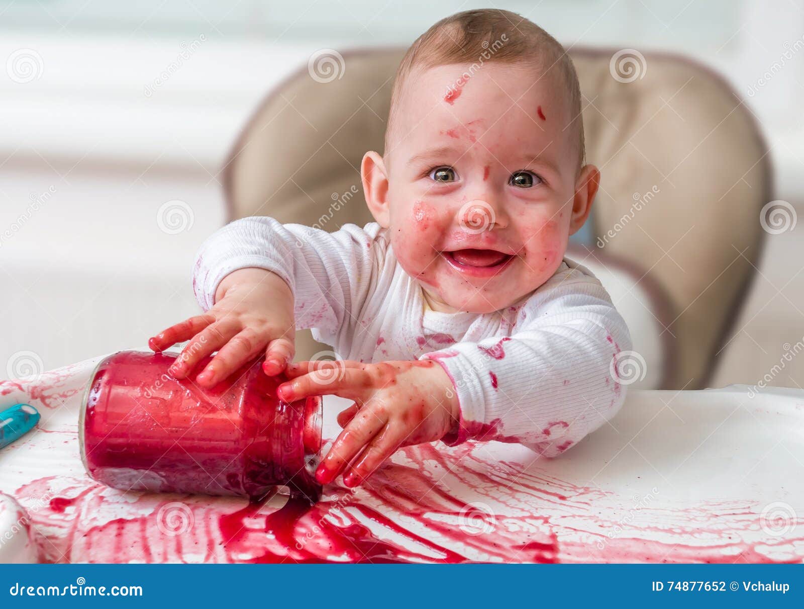 messy and dirty baby is eating snack with hands