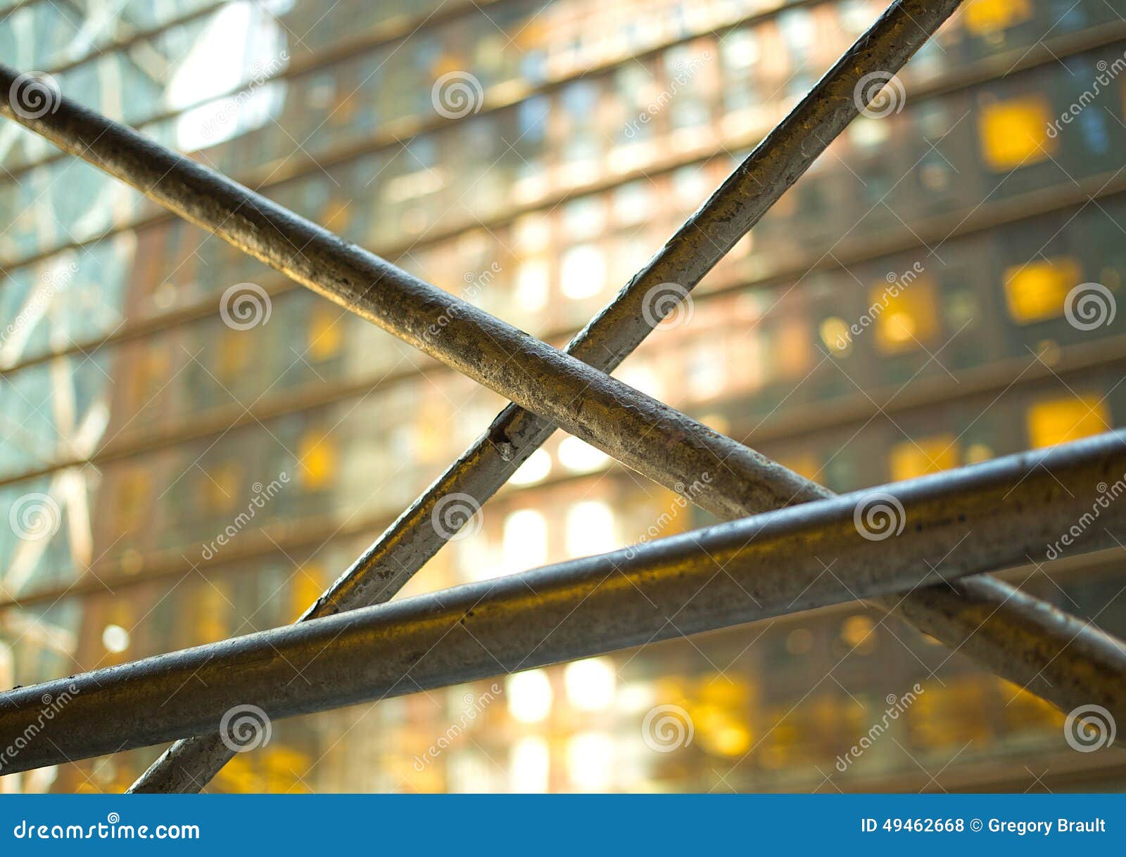 Metal Bars in Front of a Glass Building with Yellow Glowing Windows