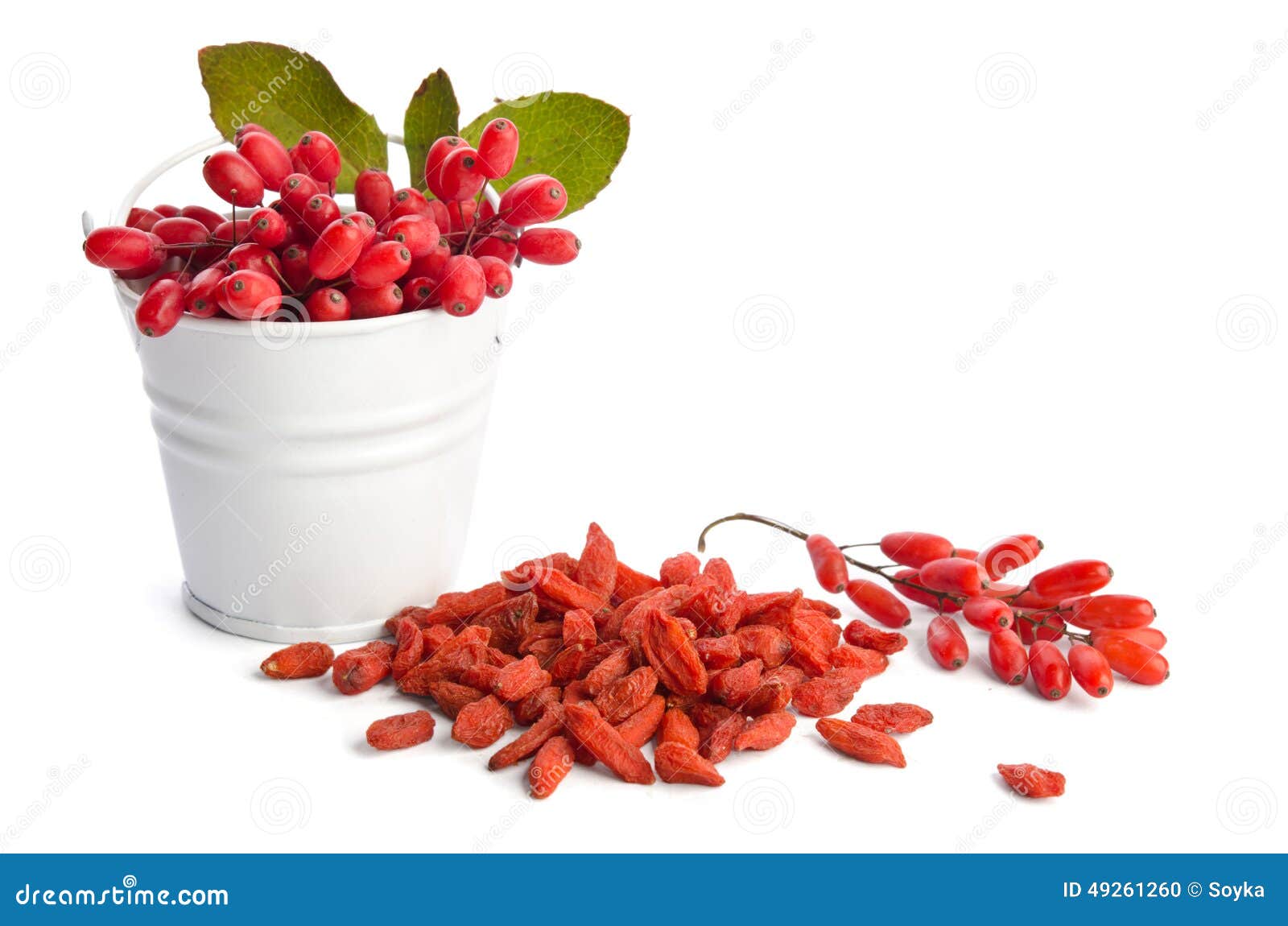 Metal bucket with berberries near heap of goji berries on white background