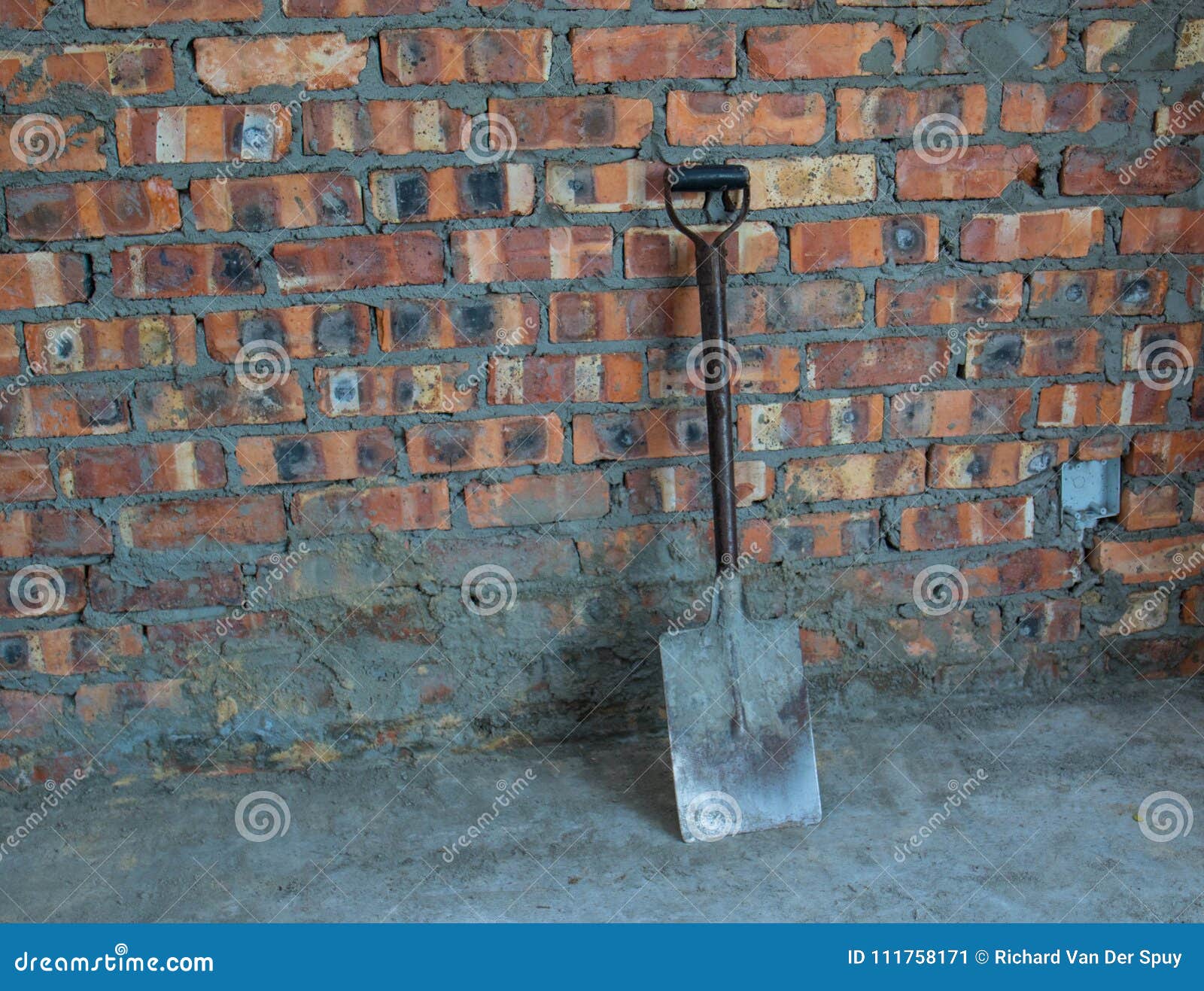 metal spade against a raw brick wall