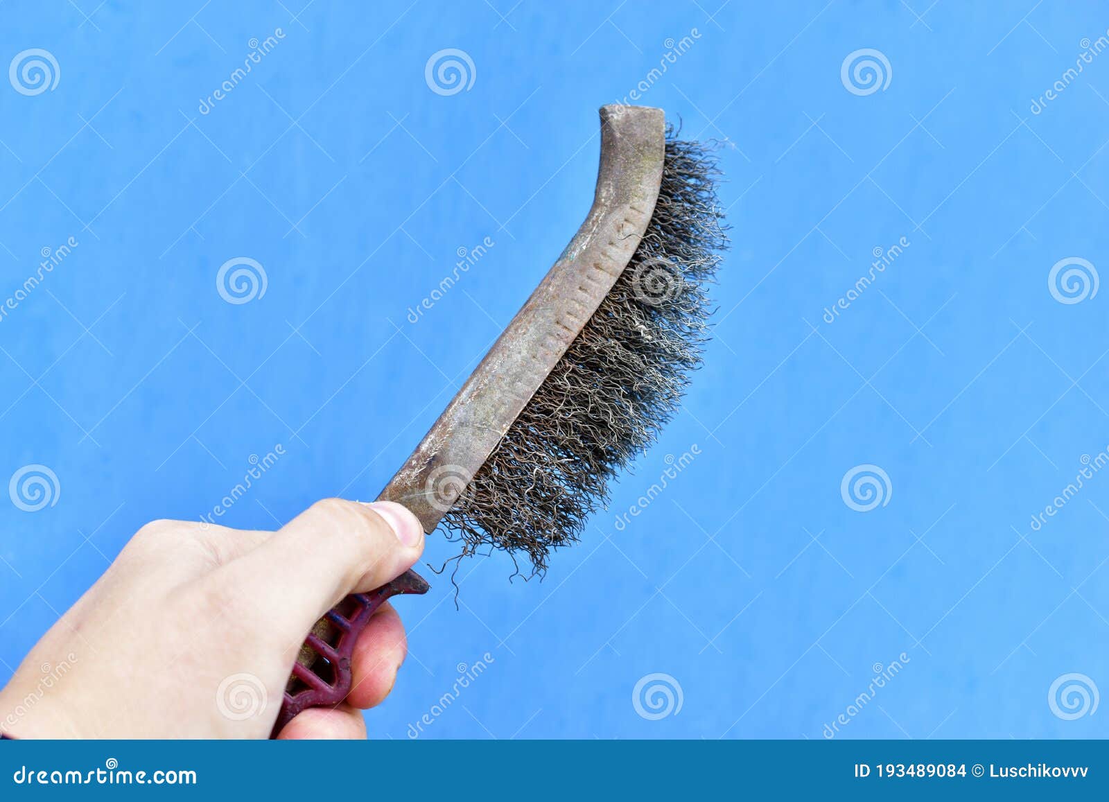 Metal Surface Cleaning Brush in Hand on a Blue Background Stock Photo