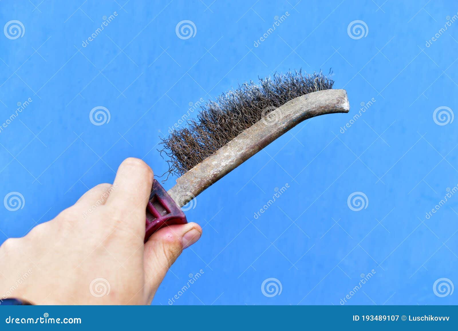 Metal Surface Cleaning Brush in Hand on a Blue Background Stock Image